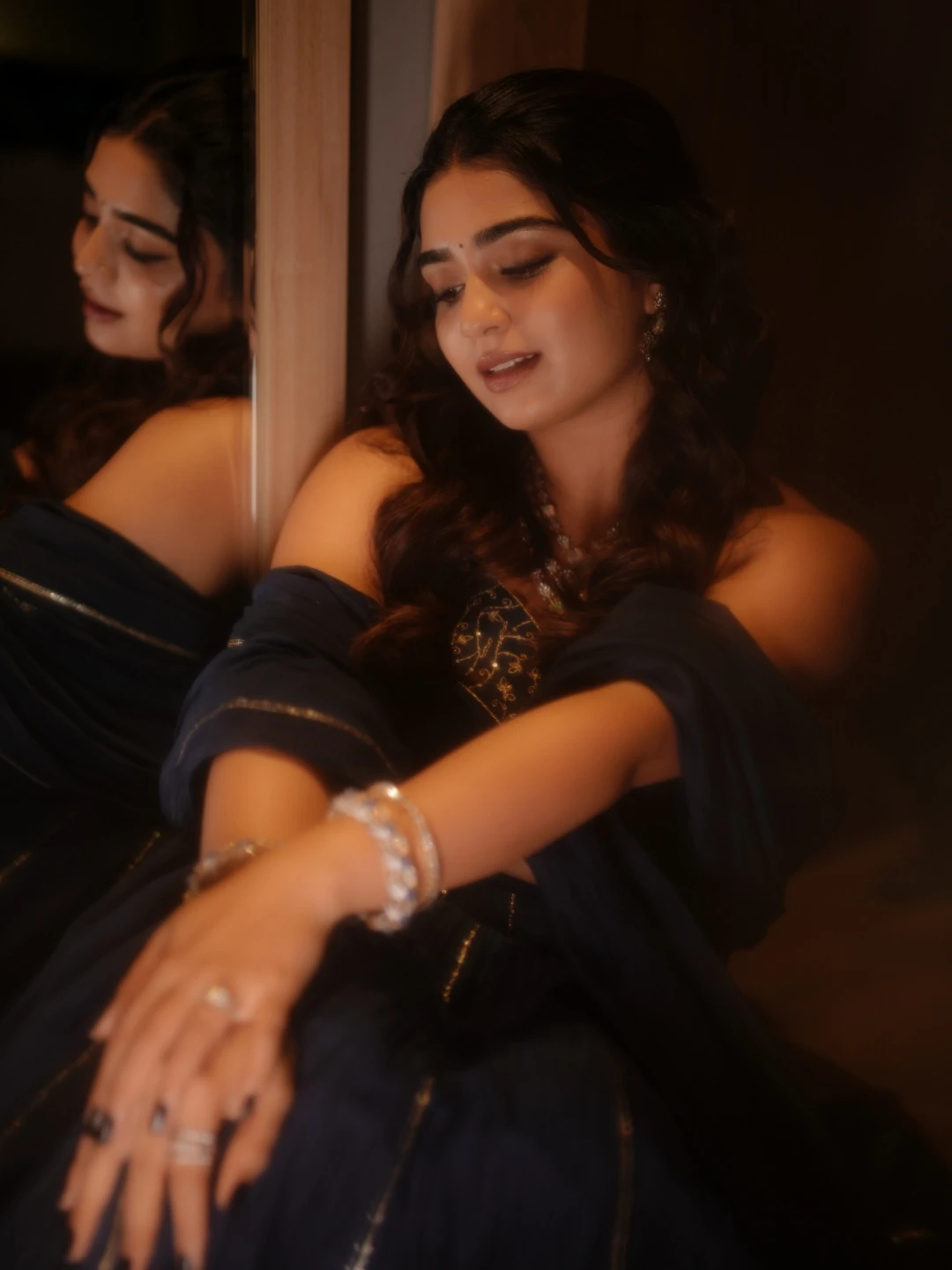 Gouri Kishan sitting against mirror in soft warm lighting photoshoot